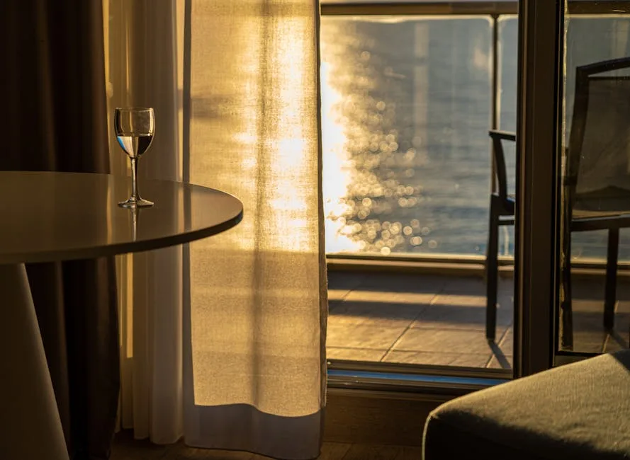 Glass on table beside sunlit balcony overlooking Naples waterfront.