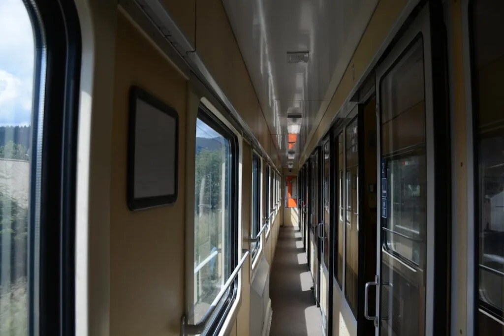 Narrow corridor inside a regional train with windows and compartments