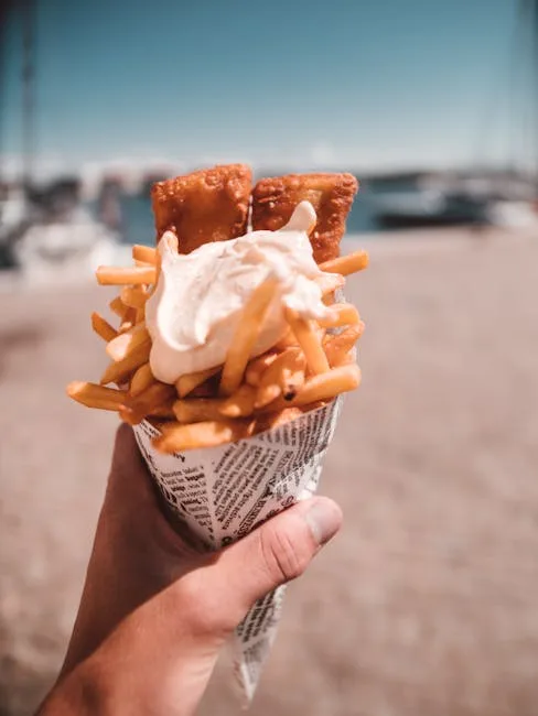 Hand holding cone of fries with creamy sauce near Naples marina