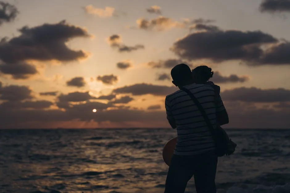 Silhouette of adult carrying child at sunset on the beach
