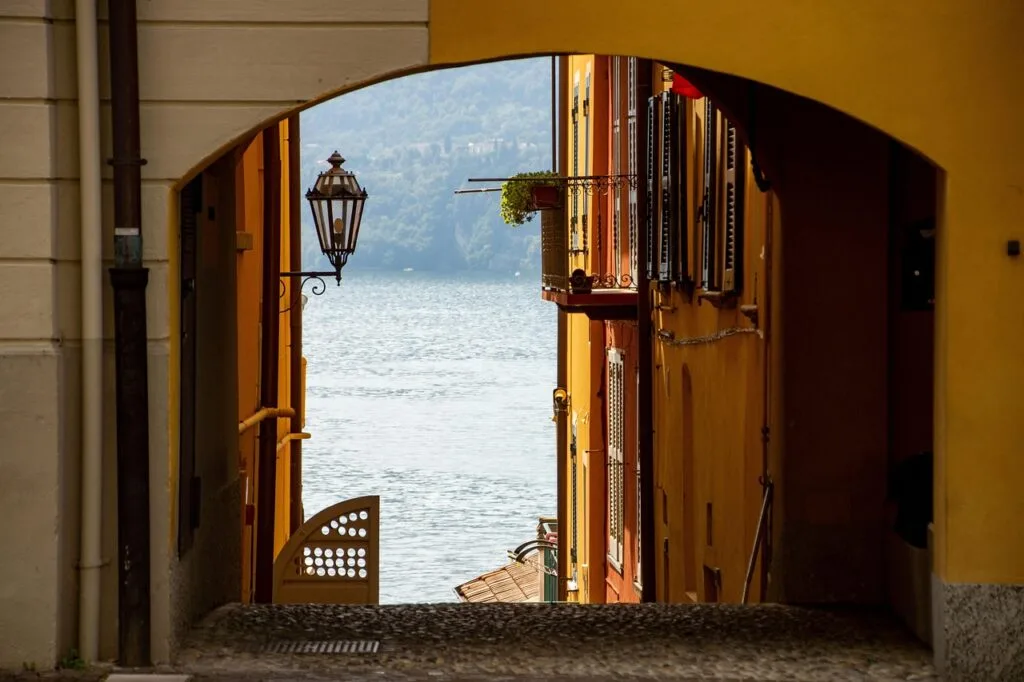 Arched alley framing shimmering sea between colorful buildings near Naples
