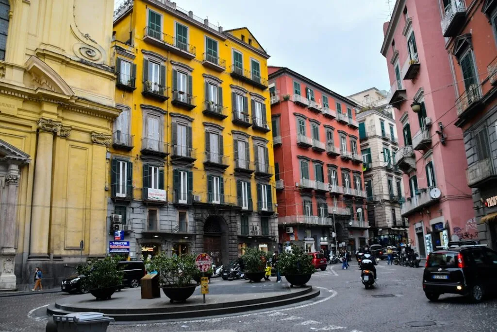 Colorful historic buildings and scooters around a small square in Naples