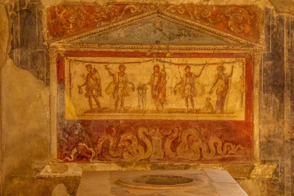 Ancient Roman fresco depicting dancing figures and serpents in Naples.