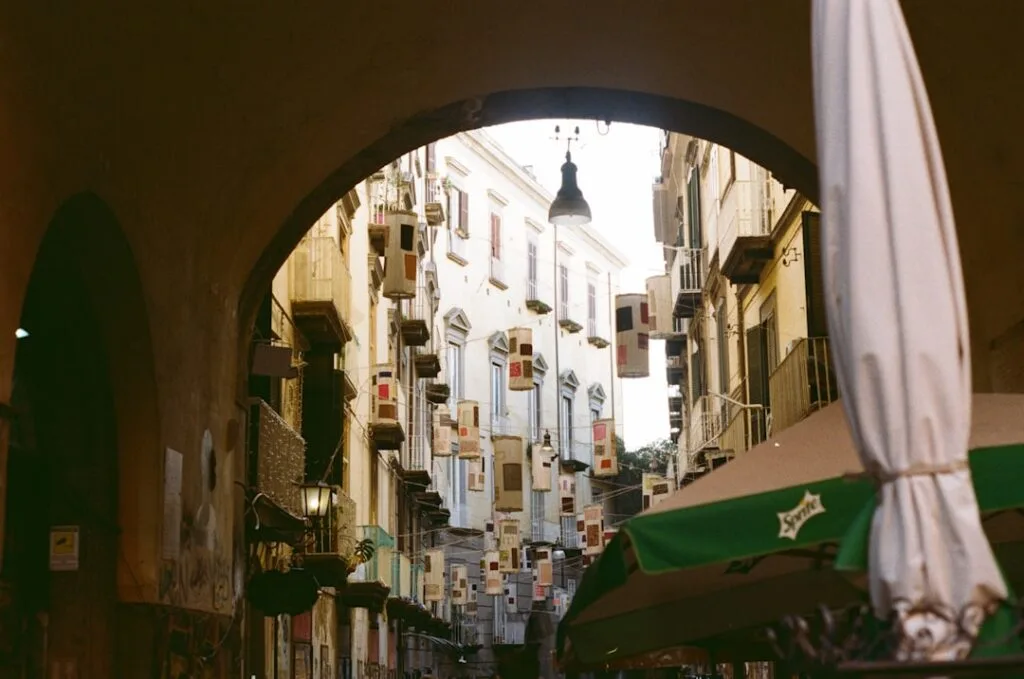 Arched doorway framing a narrow Naples street with hanging decorations