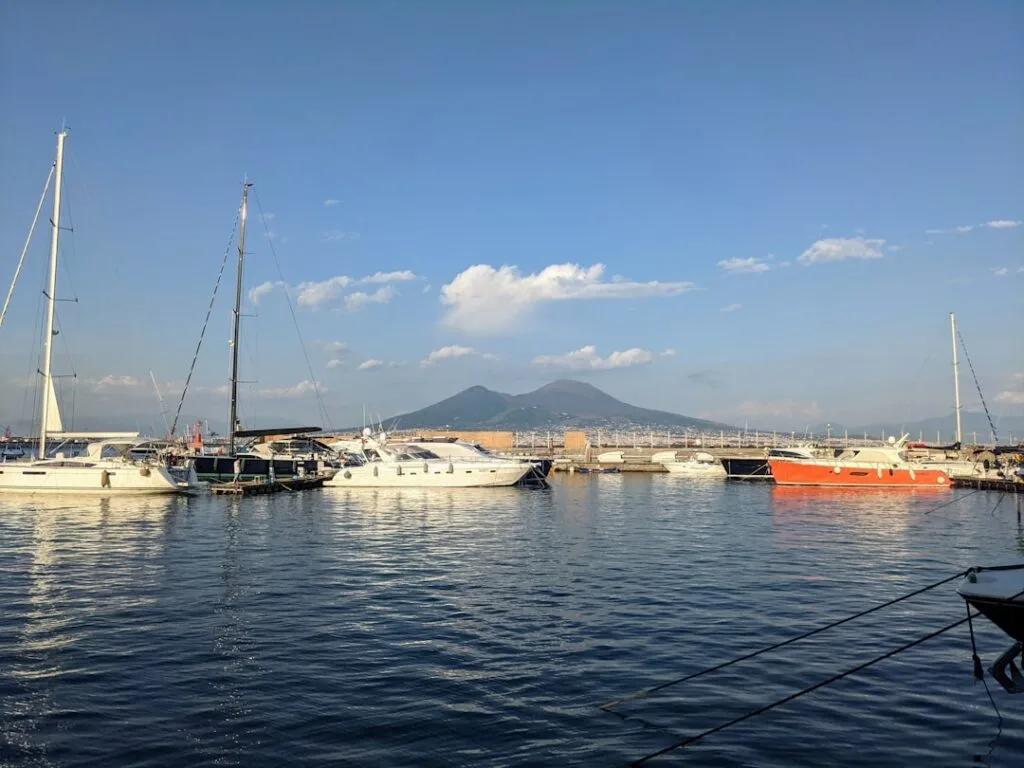 Naples harbor boats moored with Mount Vesuvius rising in background.