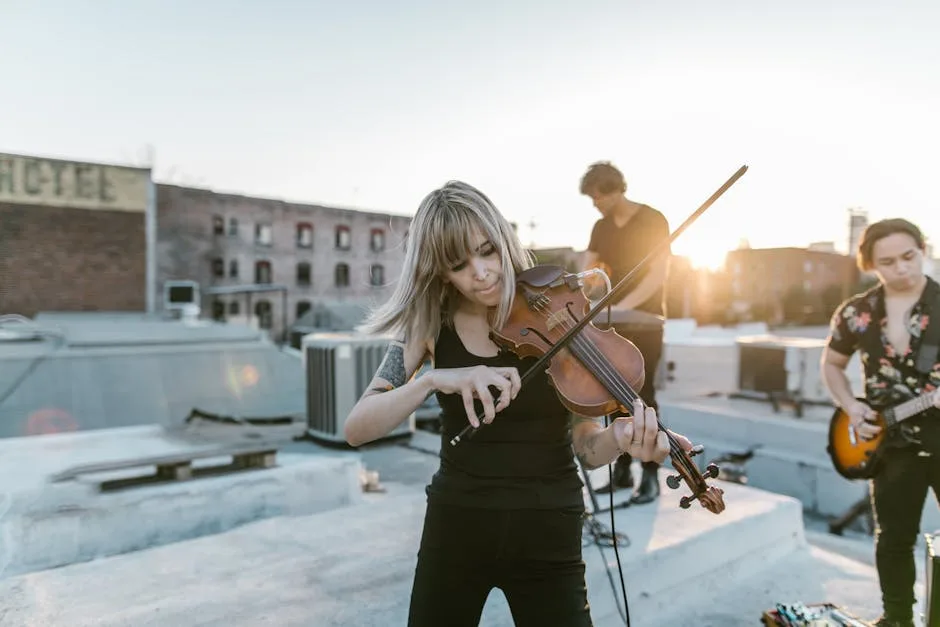 Violinist performing on a rooftop with band at sunset