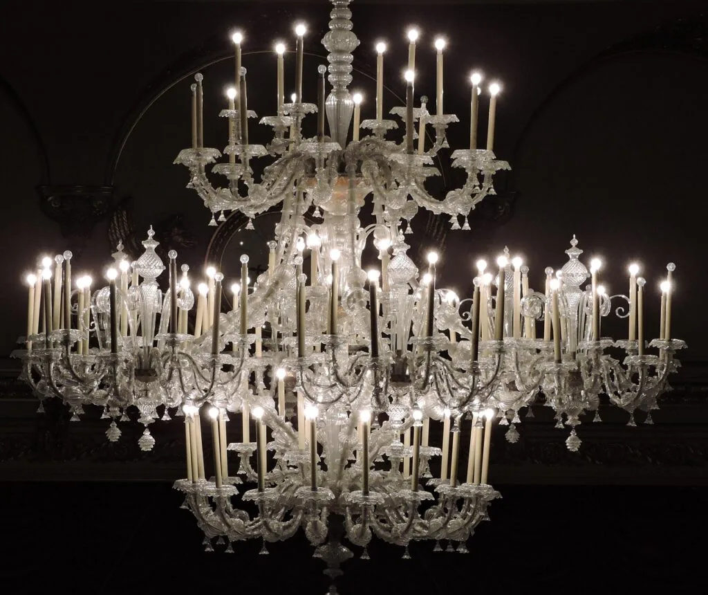 Large crystal chandelier glowing above the stage at San Carlo, Naples
