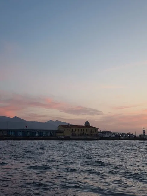 Sunset over Naples waterfront with pastel sky and silhouetted building