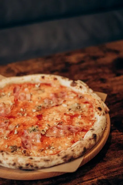 Thin-crust Neapolitan pizza with ham on wooden board in Naples