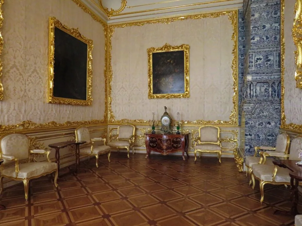 Ornate gilded salon with gold frames and chairs in Naples