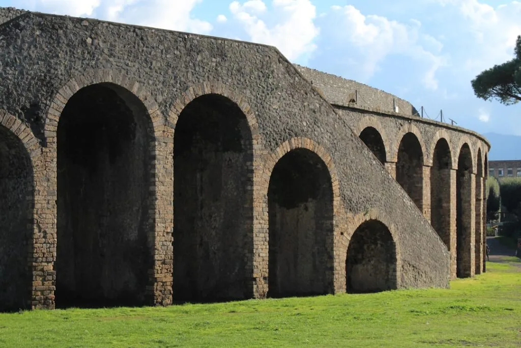 Curved Roman amphitheatre arches at Pompeii archaeological site under blue sky