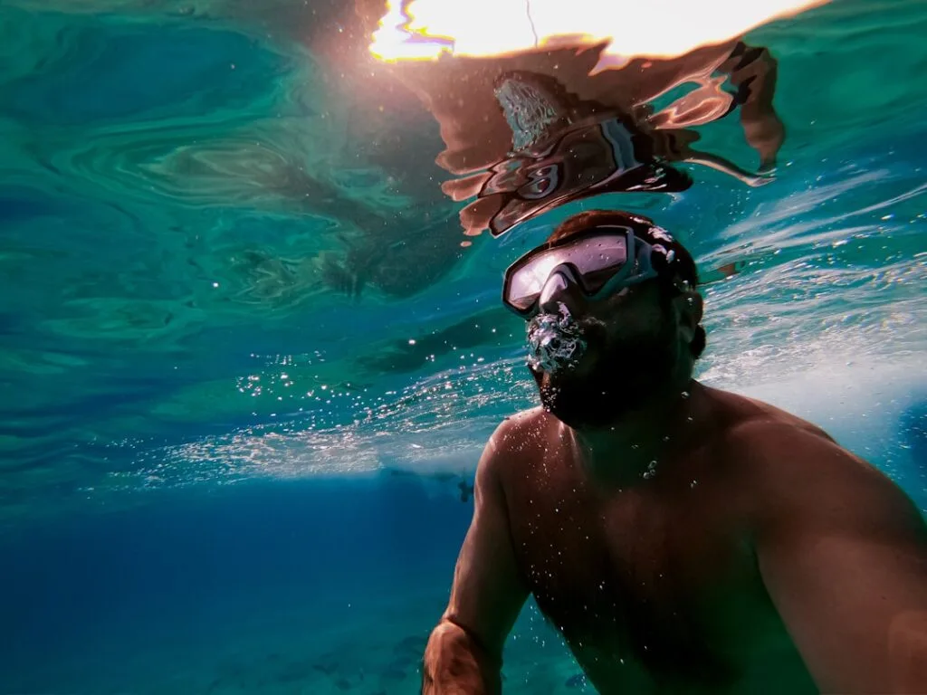 Snorkeler wearing mask underwater in clear turquoise Mediterranean sea.