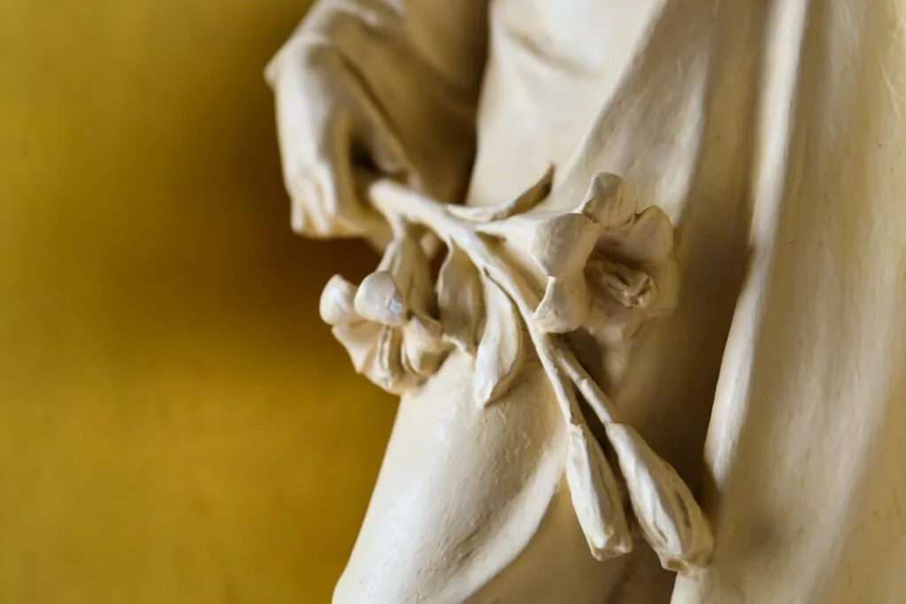 Close-up of sculpted hand holding flowers in Naples museum