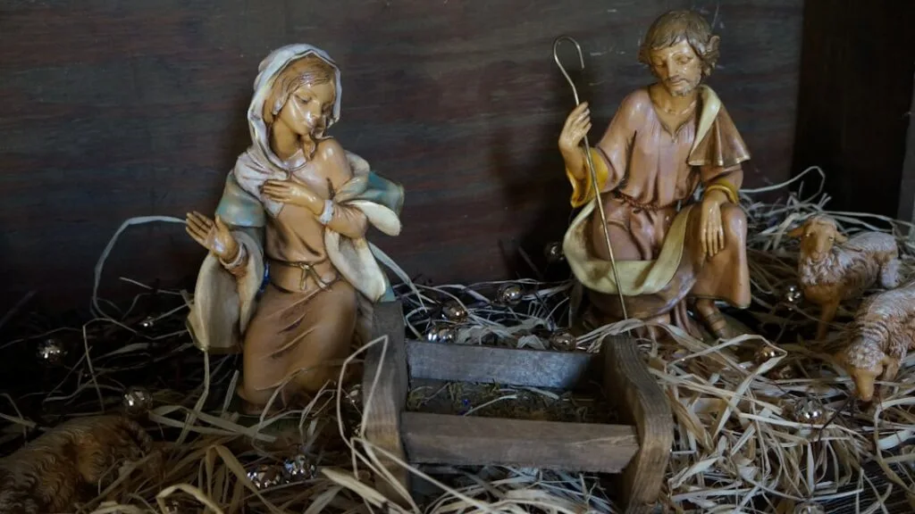Wooden nativity figurines with manger displayed in Naples church.
