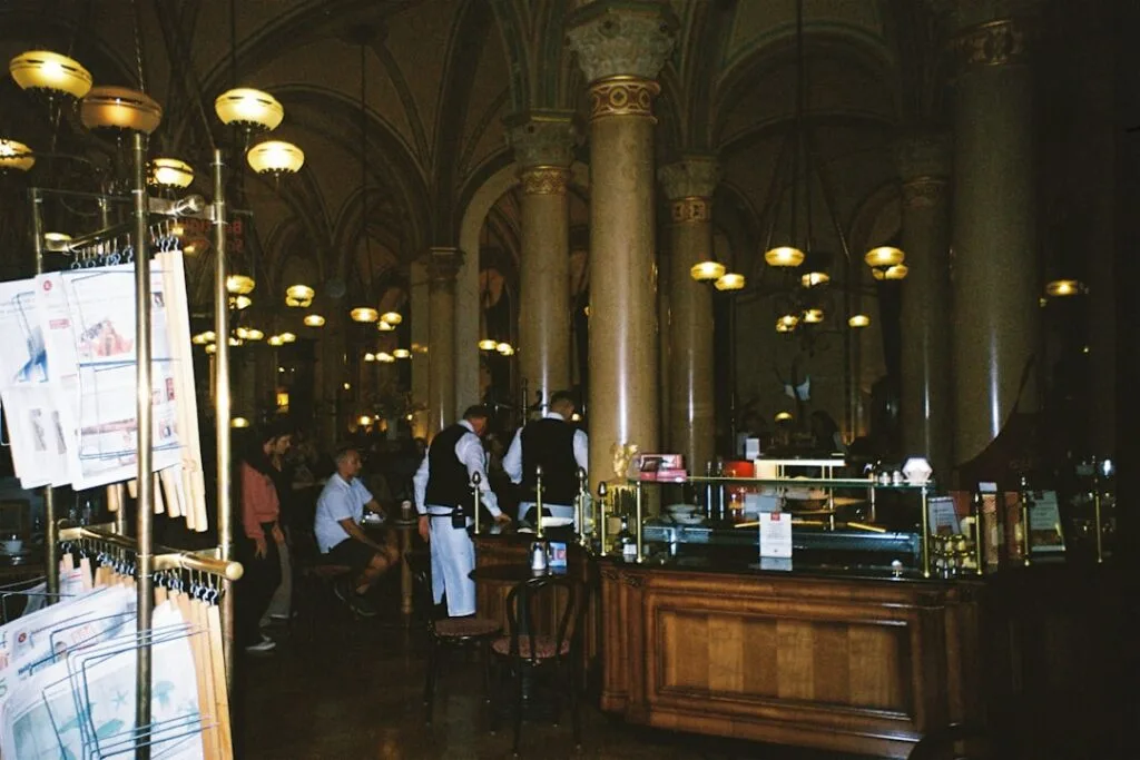 Historic Naples café interior with columns, waiters, patrons, newspaper rack