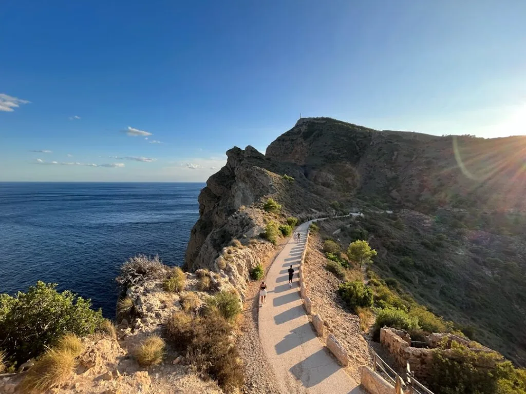 Hikers on a narrow cliffside trail along Capri's rugged coastline at sunset