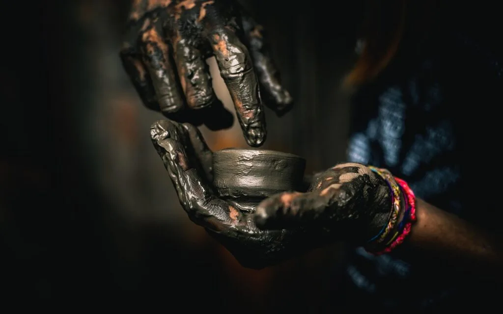 Hands covered in wet clay shaping a small pot in Naples