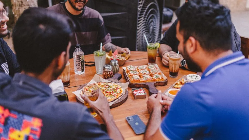 Friends sharing several pizzas and drinks around a wooden table in Naples