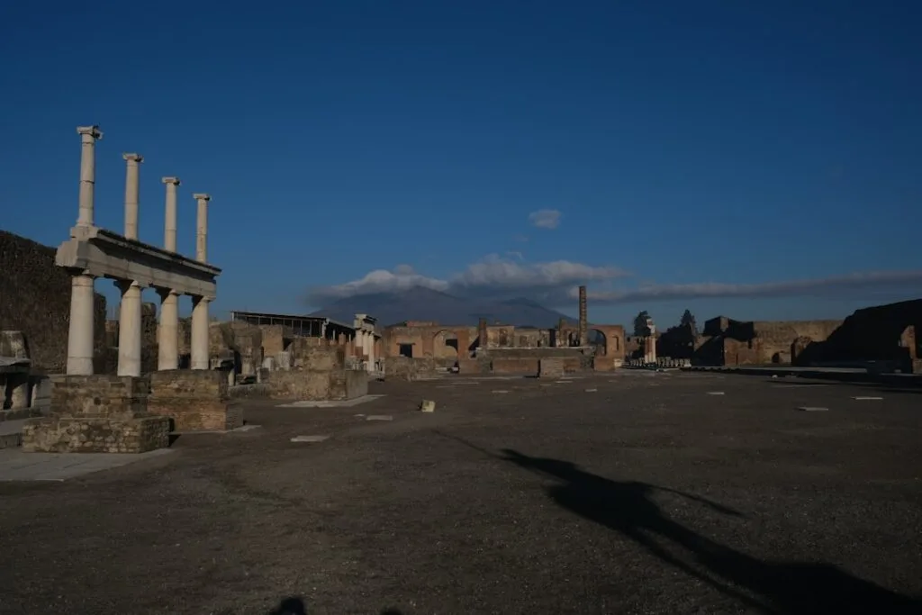 Ancient Pompeii forum ruins with Mount Vesuvius looming behind