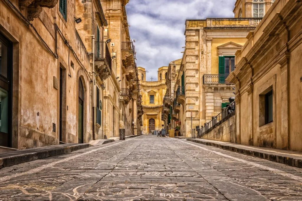 Steep cobblestone street in Naples lined with yellow Baroque buildings