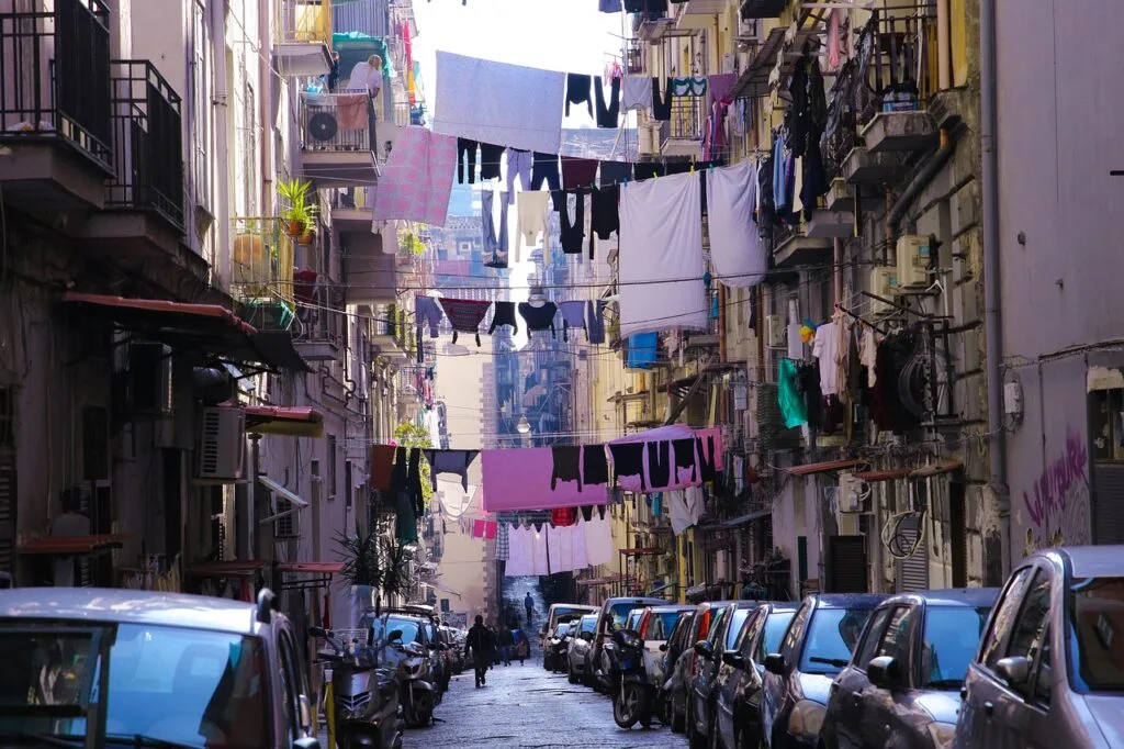 Narrow Naples street lined with parked cars and hanging laundry