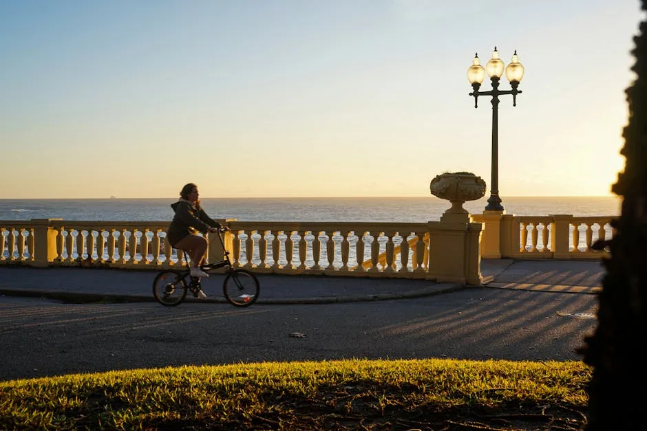 Cyclist riding along Naples waterfront promenade at golden sunset