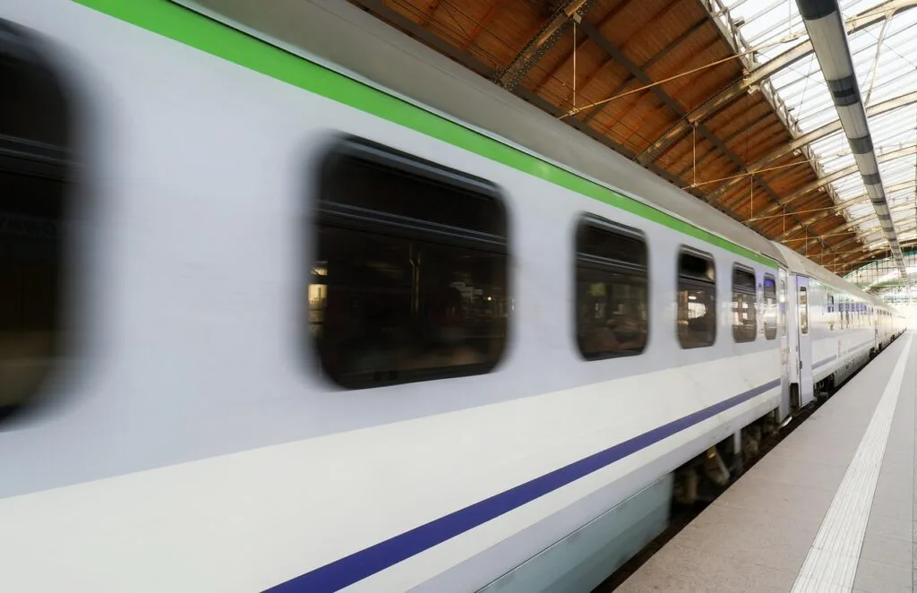High-speed train blurring past Naples station platform under glass canopy