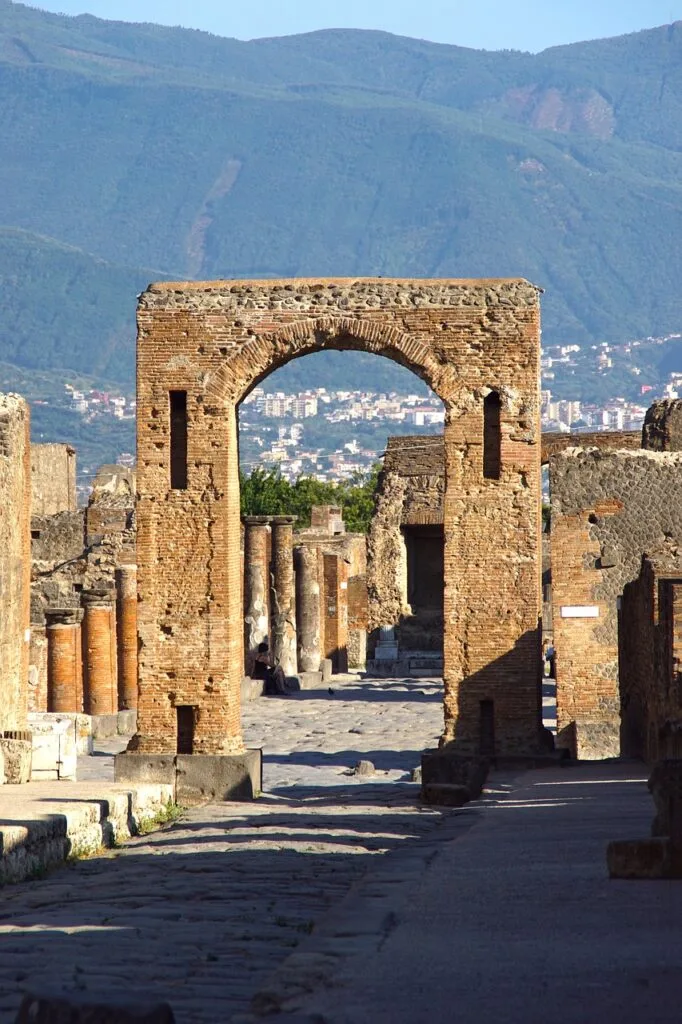 Brick archway and columns of Pompeii with distant Mount Vesuvius view