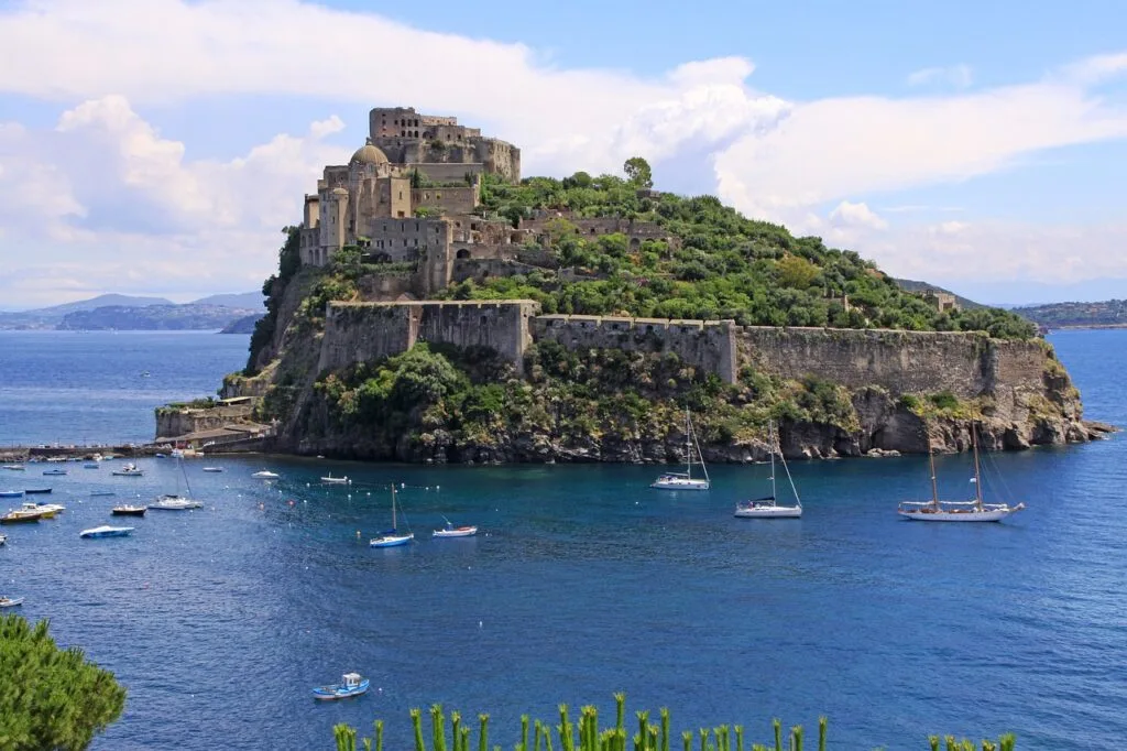 Castello Aragonese fortress on Ischia islet surrounded by sailboats near Naples