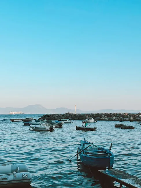 Small fishing boats anchored off Naples shore with distant ferry